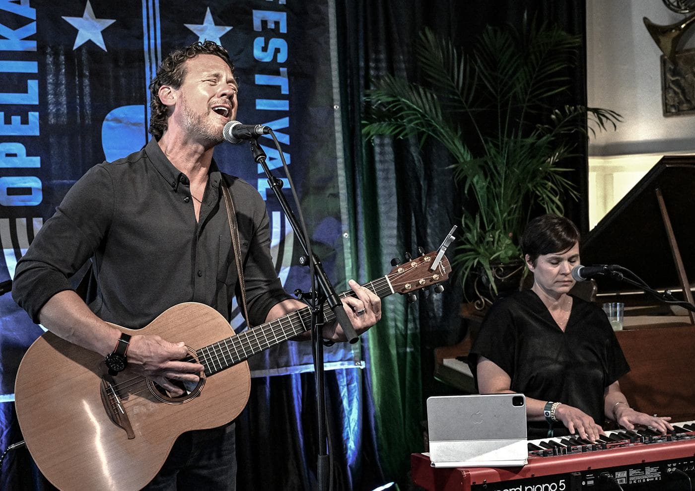 Mike Kinnebrew and Lindsay Kinnebrew performing in front of the festival banner