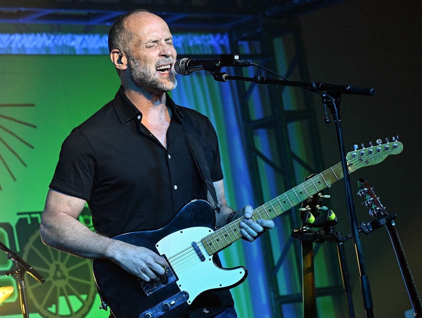Paul Thorn playing electric guitar under green stage light