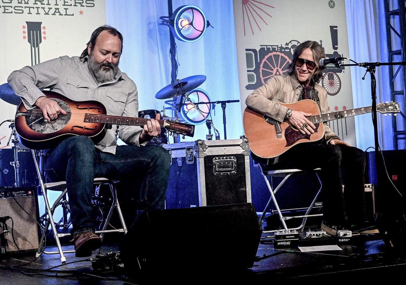 Benji Shanks and Charlie Starr seated side by side trading songs, the in-the-round format the showcase set uses