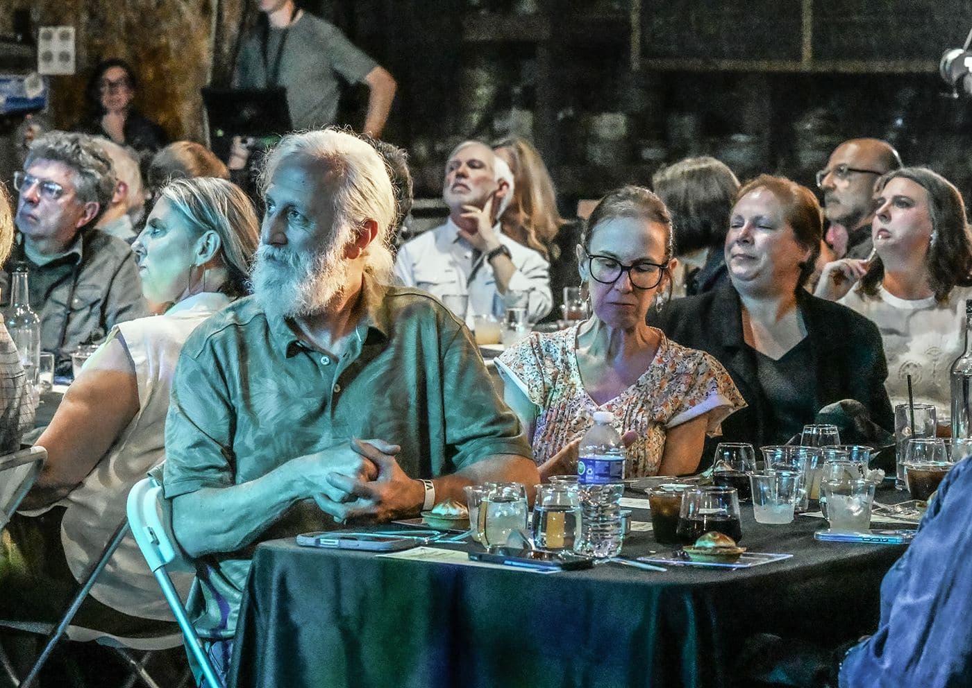 Guests at long candlelit tables during the OSF7 kickoff dinner at John Emerald Distilling Company