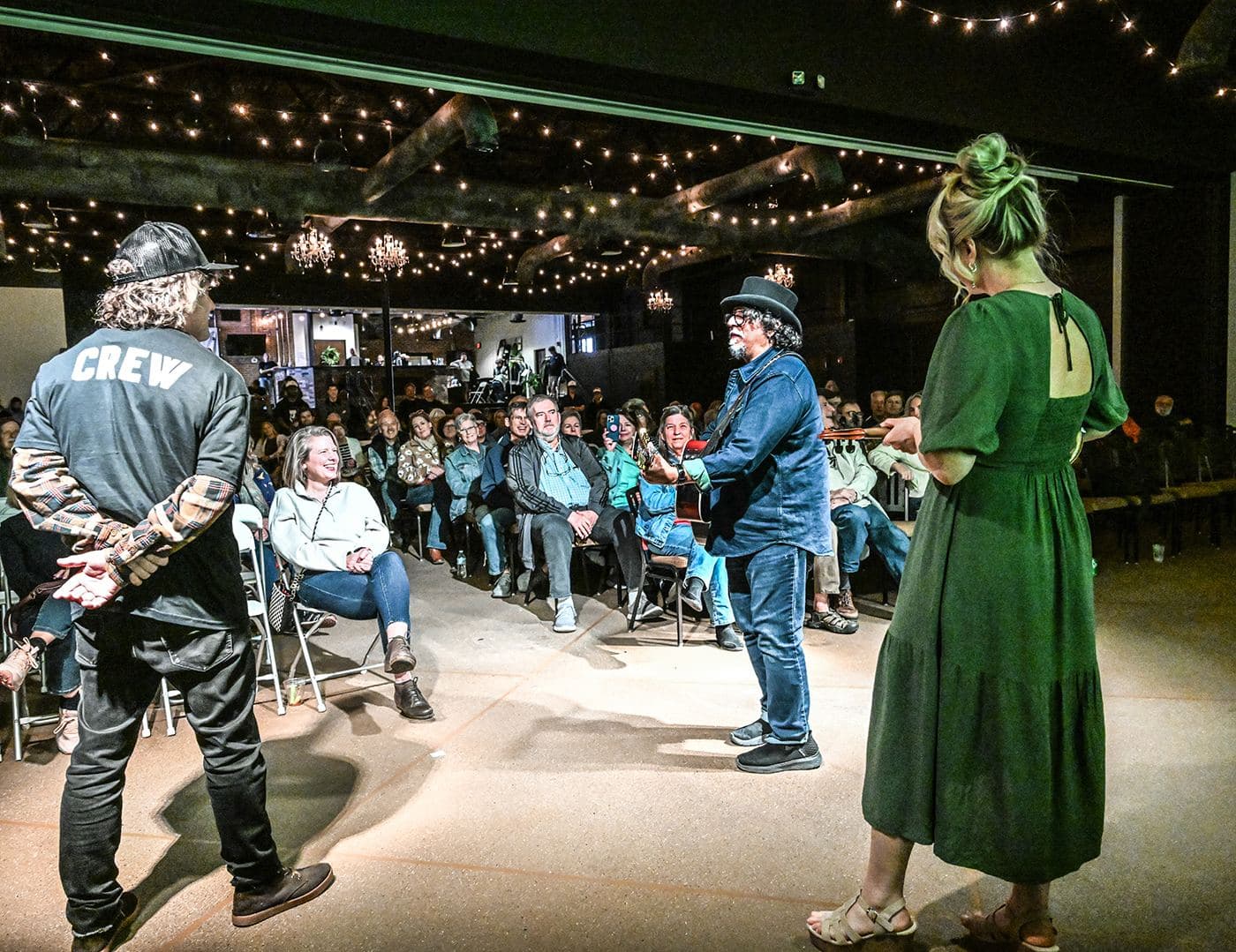 A seated crowd under string lights at the Bottling Plant Pavilion during OSF7