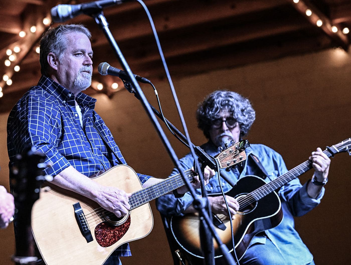 Two songwriters trading verses under warm string lights