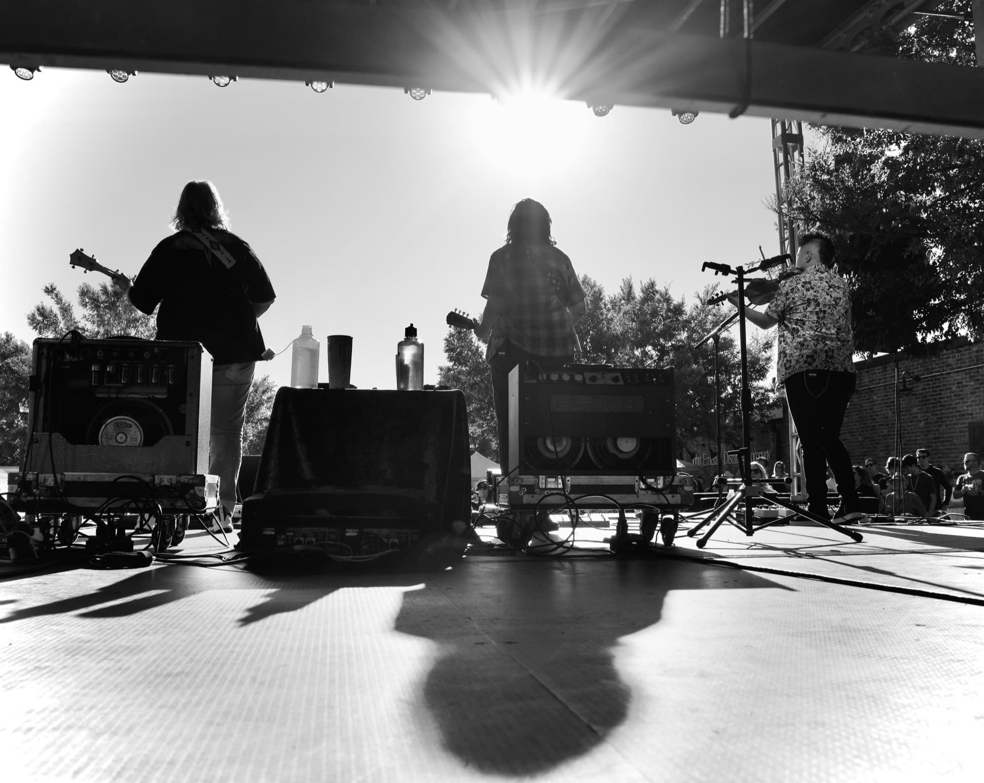 A band performing on an outdoor stage at a past Opelika Songwriters Festival